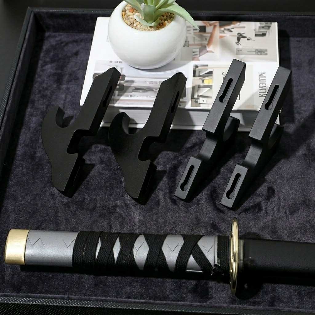 A complete set of 4 premium black wall mounts for katana display on a velvet surface with a decorative sword handle from Dreams Setup.